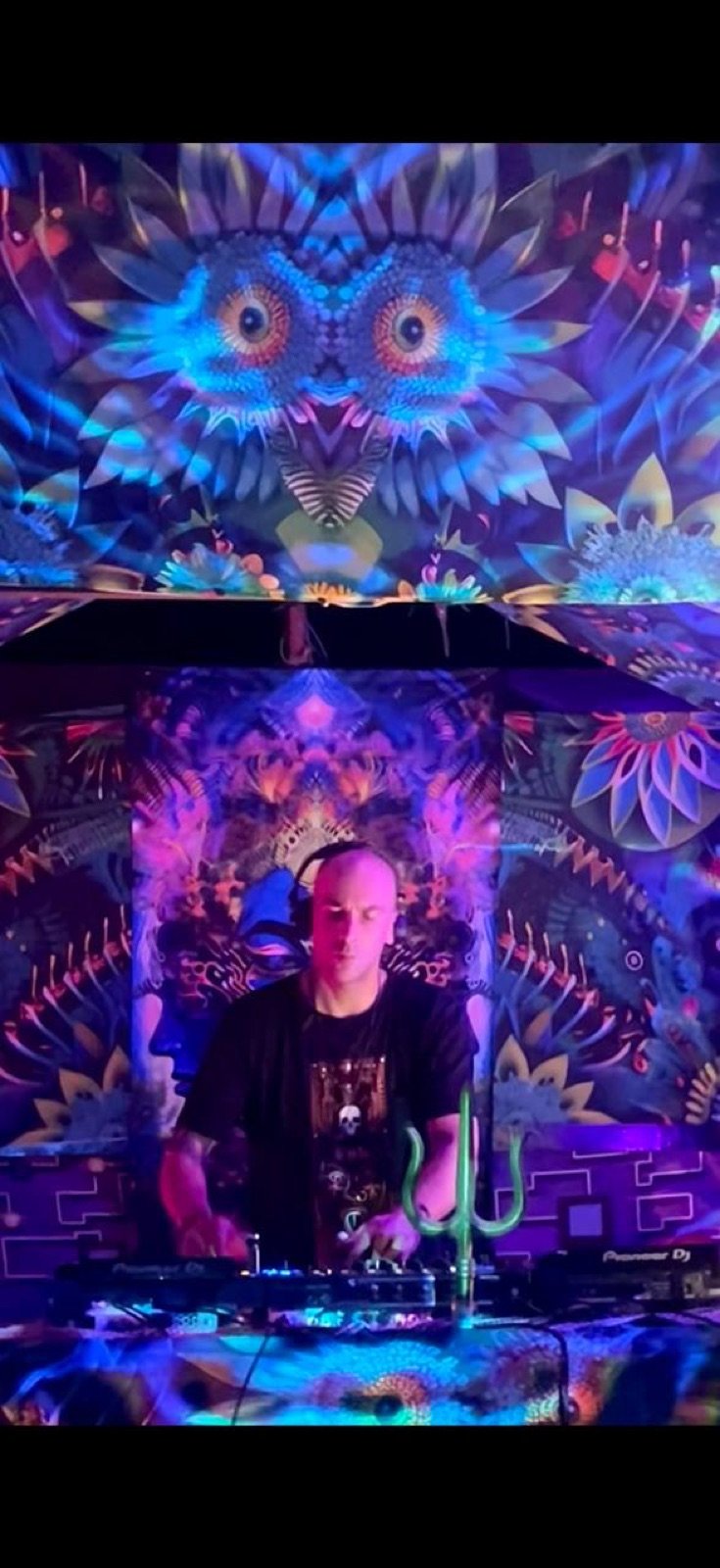 DJ performing beneath colourful psychedelic stage art
