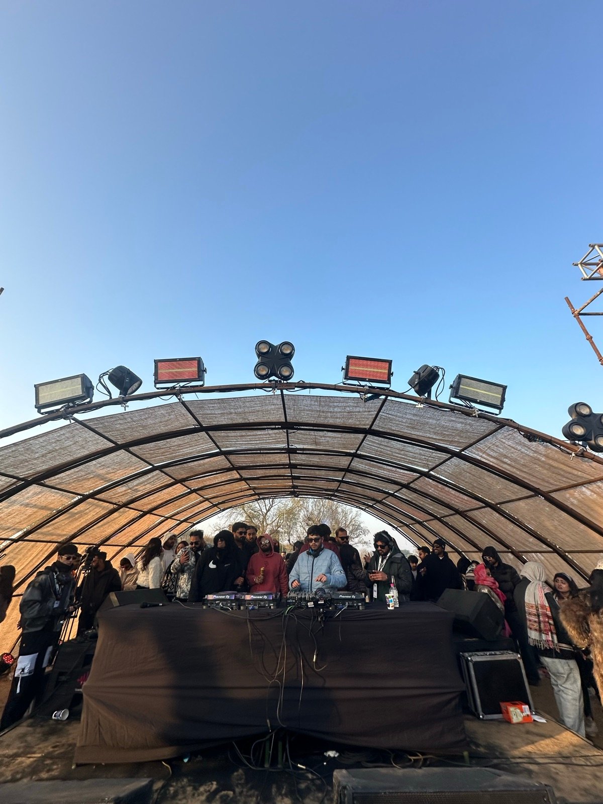 Outdoor electronic music stage beneath a clear blue sky